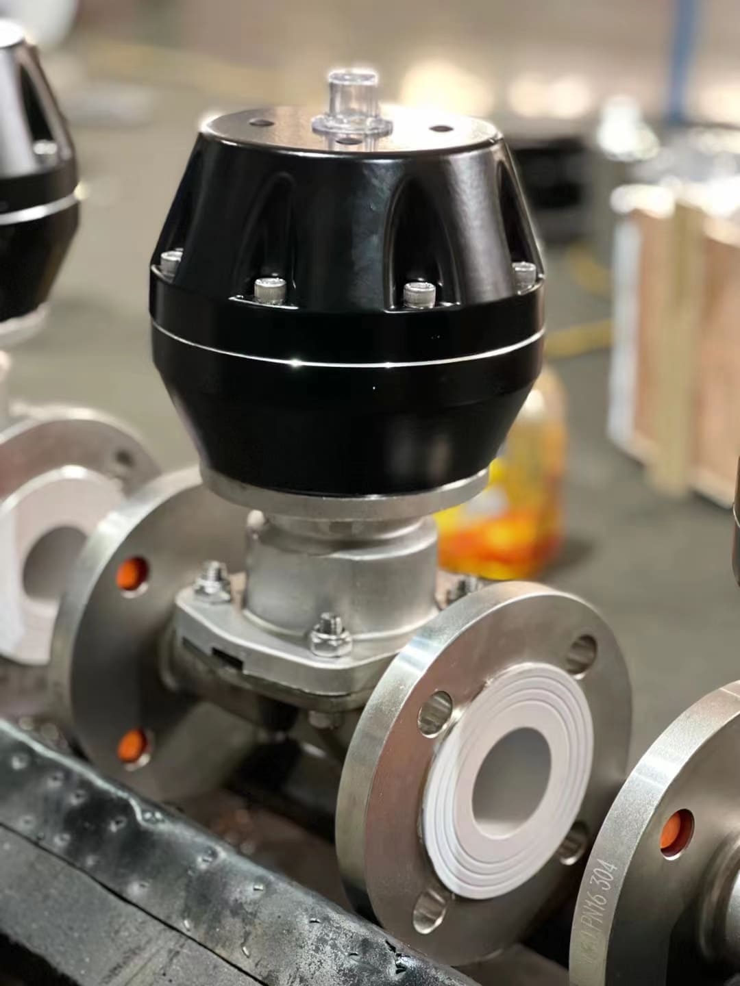 A pneumatic diaphragm valve with a white PTFE diaphragm handling chemicals in a factory