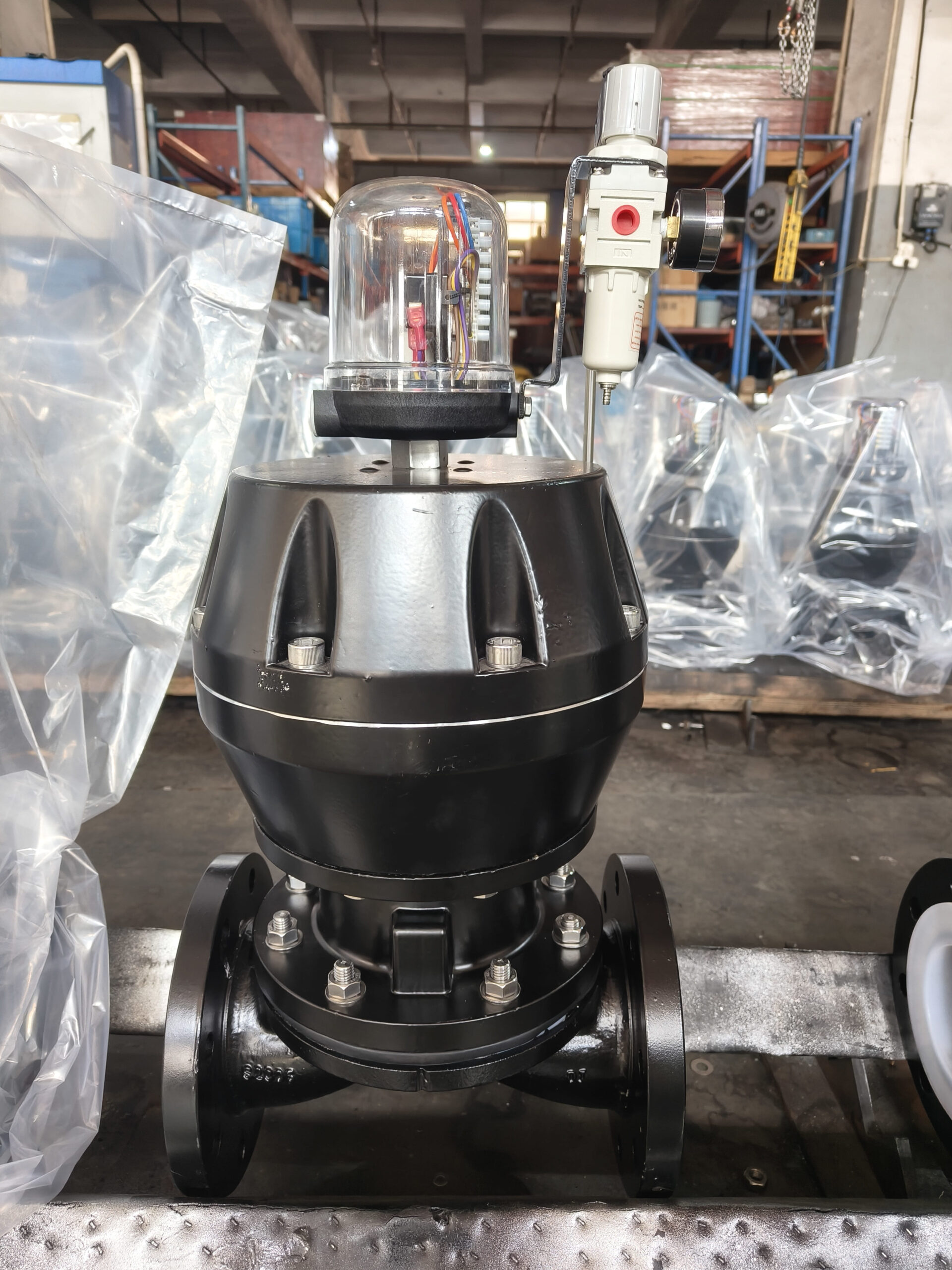 A technician inspecting a diaphragm valve with a flashlight.